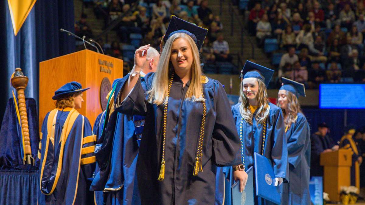 A medical student walks across the stage in December commencement.