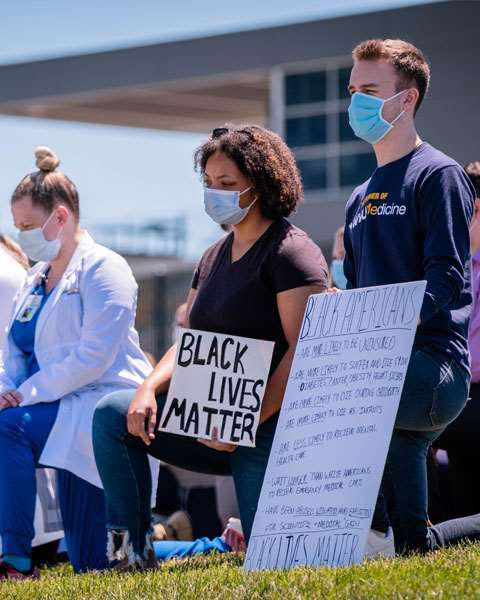 Students and staff kneeling and holding signs at a Black Lives Matter event.