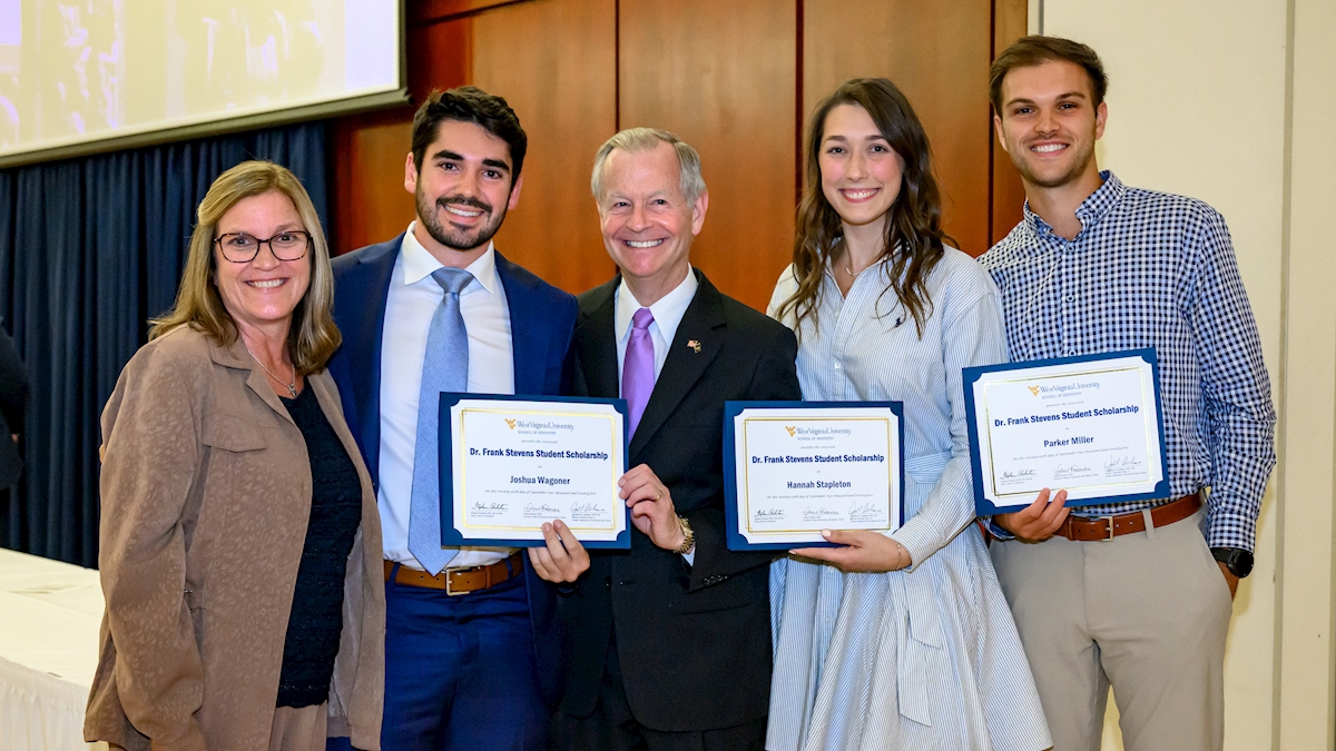 A group of students and staff hold up scholarship certificates.